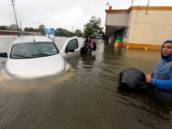 Conception Casa, center, and his friend Jose Martinez, right, check on Rhonda Worthington after her car become stuck in rising floodwaters from Tropical Storm Harvey in Houston, Texas, Monday, Aug. 28, 2017. The two men were evacuating from their home that had become flooded when they encountered Worthington's car floating off the road. (AP Photo/LM Otero)