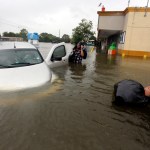 Conception Casa, center, and his friend Jose Martinez, right, check on Rhonda Worthington after her car become stuck in rising floodwaters from Tropical Storm Harvey in Houston, Texas, Monday, Aug. 28, 2017. The two men were evacuating from their home that had become flooded when they encountered Worthington's car floating off the road. (AP Photo/LM Otero)