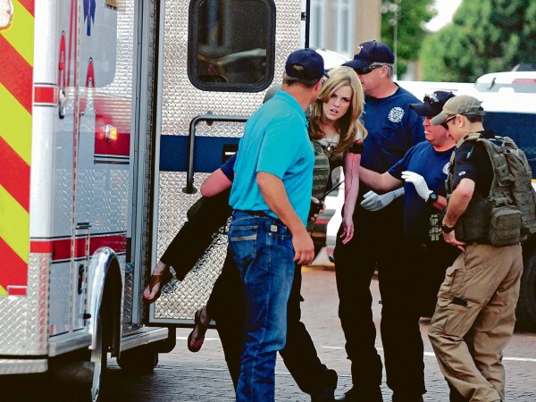 A young woman who appears to be wounded is carried to an ambulance after New Mexico state police say there has been a shooting at a public library in the eastern New Mexico community of Clovis Monday afternoon, Aug. 28, 2017. (Tony Bullocks/Eastern New Mexico News via AP)