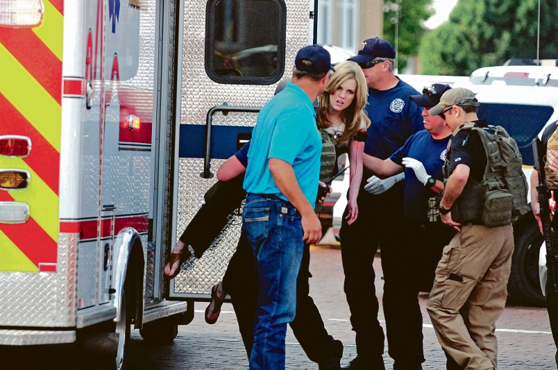 A young woman who appears to be wounded is carried to an ambulance after New Mexico state police say there has been a shooting at a public library in the eastern New Mexico community of Clovis Monday afternoon, Aug. 28, 2017. (Tony Bullocks/Eastern New Mexico News via AP)
