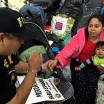 Alain Cisneros, a community organizer for the Immigrant Families and Students in the Struggle, an advocacy group known by its Spanish acronym FIEL, speaks with Adabella Fonseca, a Mexican woman whose parents brought her to the U.S. illegally when she was a year old, with her 10-month-old daughter, as he counsels Harvey evacuees who are in the country illegally at the George R. Brown Convention Center in Houston. (AP Photo by Elliot Spagat)