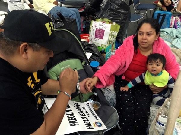Alain Cisneros, a community organizer for the Immigrant Families and Students in the Struggle, an advocacy group known by its Spanish acronym FIEL, speaks with Adabella Fonseca, a Mexican woman whose parents brought her to the U.S. illegally when she was a year old, with her 10-month-old daughter, as he counsels Harvey evacuees who are in the country illegally at the George R. Brown Convention Center in Houston. (AP Photo by Elliot Spagat)