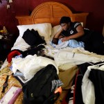 HOLD FOR STORY Jamica Batts sits on a hotel bed with her two-month-old baby Jarasiah Batts as they pack to leave Monday, Sept. 4, 2017, in Houston.  Batts and her brother Alvin may now be forced to go from the hotel they have been staying in, to a area shelter. (AP Photo/Gregory Bull)