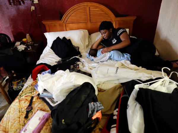 HOLD FOR STORY Jamica Batts sits on a hotel bed with her two-month-old baby Jarasiah Batts as they pack to leave Monday, Sept. 4, 2017, in Houston.  Batts and her brother Alvin may now be forced to go from the hotel they have been staying in, to a area shelter. (AP Photo/Gregory Bull)