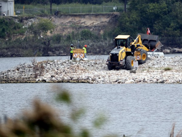 HOLD FOR STORY BY MICHAEL BIESECKER--Workers are shown at San Jacinto River Waste Pits near the Interstate 10 bridge over the river Wednesday, Sept. 13, 2017, in Channelview, Texas. (AP Photo/David J. Phillip)