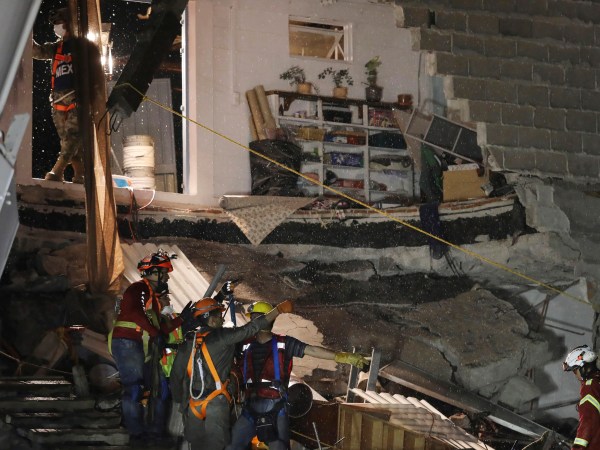Rescue workers evacuate by rain the collapsed office building at the corner of Alvaro Obregon and Yucatan streets in Mexico City, early Monday Sept 25, 2017. Search teams are still digging in dangerous piles of rubble hoping against the odds to find survivors at collapsed buildings. (AP Photo/Miguel Tovar)