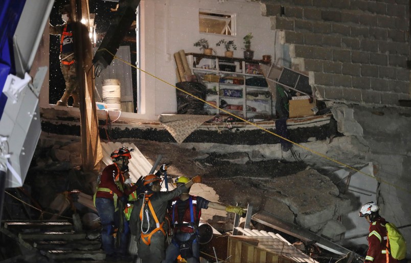 Rescue workers evacuate by rain the collapsed office building at the corner of Alvaro Obregon and Yucatan streets in Mexico City, early Monday Sept 25, 2017. Search teams are still digging in dangerous piles of rubble hoping against the odds to find survivors at collapsed buildings. (AP Photo/Miguel Tovar)