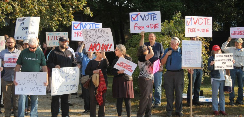 Protesters gather on Tuesday, Sept. 12, 2017, at Saint Anselm College in Manchester, New Hampshire, ahead of a  day-long meeting of the Trump administration’s election integrity commission. They argue the commission, which is tasked with investigating voter fraud, is a sham. Signs reading “Vote Free or Die” played off New Hampshire’s motto: “Live Free or Die.” (AP Photo/Holly Ramer).