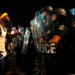 A man yells at police in riot gear just before a crowd turned violent Saturday, Sept. 16, 2017, in University City, Mo. Earlier, protesters marched peacefully in response to a not guilty verdict in the trial of former St. Louis police officer Jason Stockley . (AP Photo/Jeff Roberson)