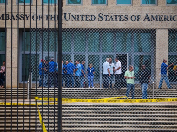 Staff stand within the United States embassy facility in Havana, Cuba, Friday, Sept. 29, 2017. The United States issued an ominous warning to Americans on Friday to stay away from Cuba and ordered home more than half the U.S. diplomatic corps, acknowledging neither the Cubans nor America’s FBI can figure out who or what is responsible for months of mysterious health ailments. (AP Photo/Desmond Boylan)
