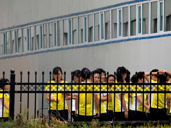In this Sept. 5, 2017, photo, North Korean workers gather after lunch at the Hong Chao Zhi Yi garment factory in Hunchun in northeastern China's Jilin province. At a time when North Korea faces sanctions on many exports, the outsourcing of tens of thousands of workers worldwide brings in revenue estimated at anywhere from $200 million to $500 million. That could account for a sizable portion of its nuclear weapons and missile programs, which South Korea says has cost well over $1 billion. (AP Photo/Ng Han Guan)