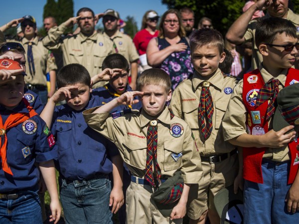 Eli Whalen, 10, center, purses his lip as he salutes the lives of fallen soldiers who have made the ultimate sacrifice dying for their country in battle while paying his respects alongside fellow Boy Scouts and Cub Scouts alike on Memorial Day amidst hundreds of families attending a ceremony on Monday, May 29, 2017 at Fairview Cemetery in Linden, Mich. (Jake May /The Flint Journal-MLive.com via AP)
