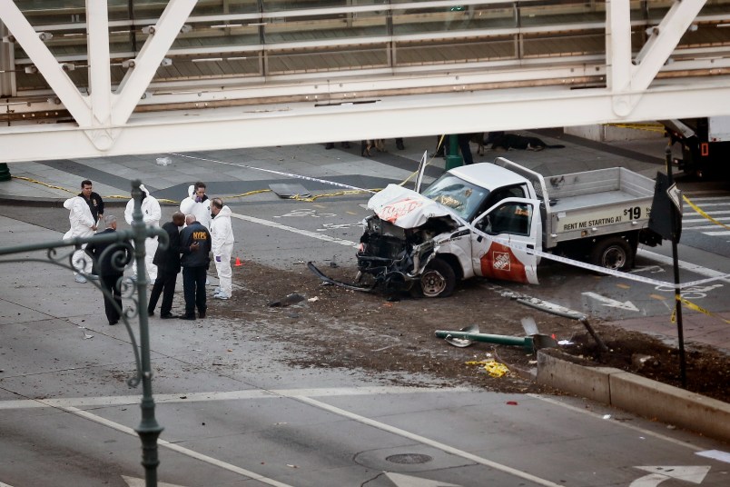 Investigators stand near the wreckage of a Home Depot truck at an overpass for Stuyvesant High School, Tuesday Oct. 31, 2017, in New York. (AP Photo/Bebeto Matthews)