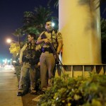 Police officers take cover near the scene of a shooting near the Mandalay Bay resort and casino on the Las Vegas Strip, Sunday, Oct. 1, 2017, in Las Vegas. (AP Photo/John Locher)