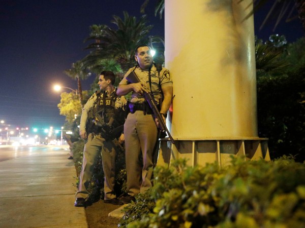 Police officers take cover near the scene of a shooting near the Mandalay Bay resort and casino on the Las Vegas Strip, Sunday, Oct. 1, 2017, in Las Vegas. (AP Photo/John Locher)