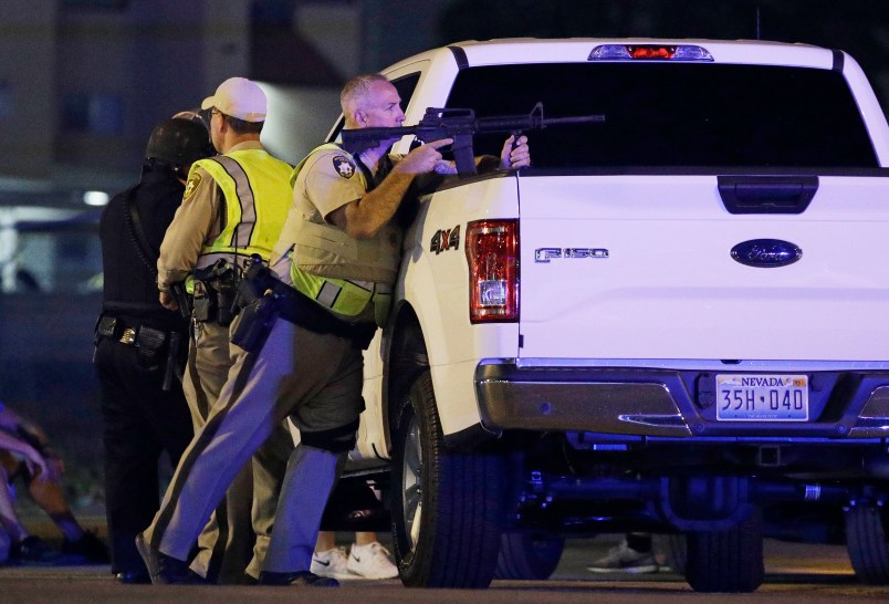 A police officer takes cover behind a truck at the scene of a shooting near the Mandalay Bay resort and casino on the Las Vegas Strip, Sunday, Oct. 1, 2017, in Las Vegas. (AP Photo/John Locher)