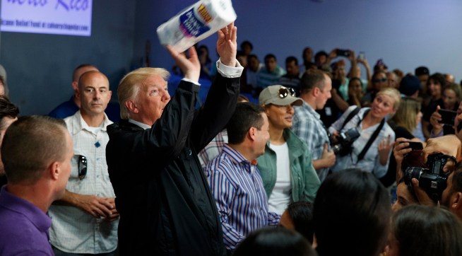 President Donald Trump tosses paper towels into a crowd as he hands out supplies at Calvary Chapel, Tuesday, Oct. 3, 2017, in Guaynabo, Puerto Rico. (AP Photo/Evan Vucci)