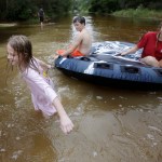 Crimson Peters, 7, left, Tracy Neilsen, 13, center, and Macee Nelson, 15, ride an inter tube in down a flooded street after Hurricane Nate, Sunday, Oct. 8, 2017, in Coden, Ala. (AP Photo/Brynn Anderson)