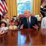 President Donald Trump talks with Claire Thomas, 5, far left, from Washington, before  passing out candy to children dressed in their halloween costumes in the Oval Office of the White House, Friday, Oct. 27, 2017. The White House had invited the children of members of the media to visit the president and to trick-o-treat on the White House complex of the Eisenhower Executive Office building. (AP Photo/Pablo Martinez Monsivais)