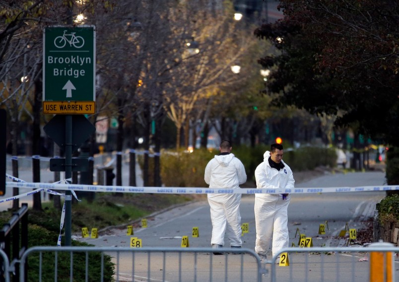 Emergency officials walk near evidence markers on the west side bike path in lower Manhattan, New York, Wednesday, Nov. 1, 2017. Investigators worked through the night to determine what led a truck driver to plow down people on a riverfront bike path near the World Trade Center, brandishing air guns and yelling “God is great” in Arabic as his deadly route of terror ended with a crash, authorities said. (AP Photo/Seth Wenig)