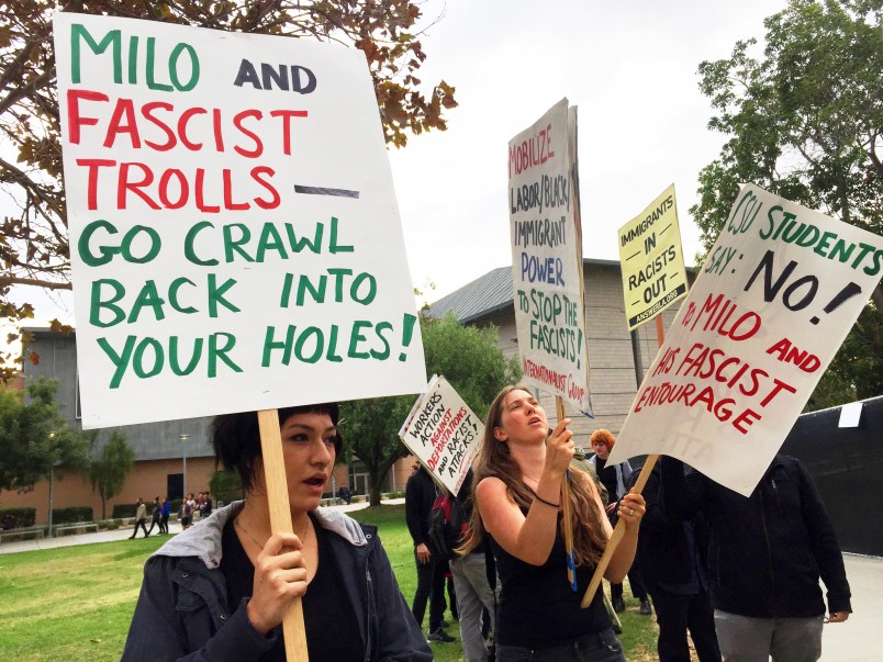 Demonstrators protest outside a speech by conservative provocateur Milo Yiannopoulos, sponsored by a Republican student group at California State University, Fullerton, Tuesday, Oct. 31, 2017. At least one fight broke out and seven people were arrested. Protesters stood outside barricades chanting "Black lives matter," and "Cops and the Klan go hand in hand." They were mostly peaceful, but one woman protesting the event attacked a Yiannopoulos supporter with punches before a third person subdued her with pepper spray. (AP Photo/Amanda Lee Myers)