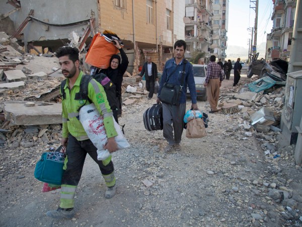 In this photo provided by Tasnim News Agency, people carry belongings after the earthquake at Sarpol-e-Zahab town in western Iran, Monday, Nov. 13, 2017. A powerful 7.3 magnitude earthquake that struck the Iraq-Iran border region killed more than three hundreds people in both countries, sent people fleeing their homes into the night and was felt as far west as the Mediterranean coast, authorities reported on Monday. (Farzad Menati/Tasnim News Agency via AP)