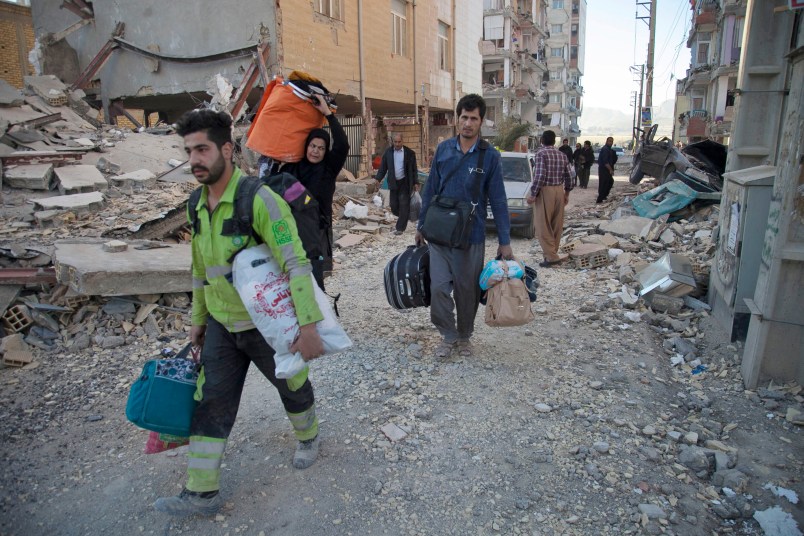 In this photo provided by Tasnim News Agency, people carry belongings after the earthquake at Sarpol-e-Zahab town in western Iran, Monday, Nov. 13, 2017. A powerful 7.3 magnitude earthquake that struck the Iraq-Iran border region killed more than three hundreds people in both countries, sent people fleeing their homes into the night and was felt as far west as the Mediterranean coast, authorities reported on Monday. (Farzad Menati/Tasnim News Agency via AP)