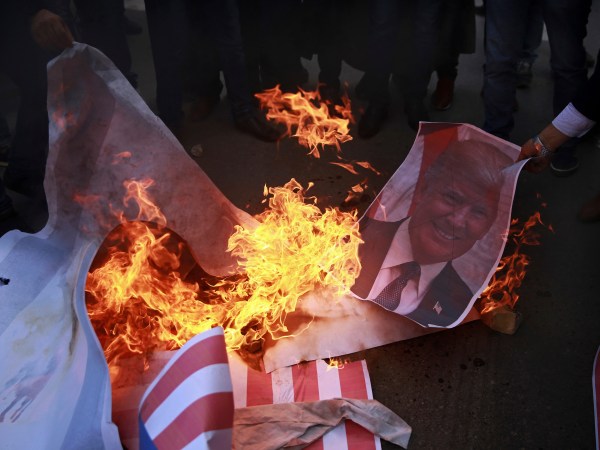 Palestinian protesters burn a poster of U.S. President Donald Trump and mocks of Israeli and American flags, during a protest against US decision to recognize Jerusalem as Israel’s capital, in Gaza City Thursday, Dec. 7, 2017. (AP Photo/ Khalil Hamra)