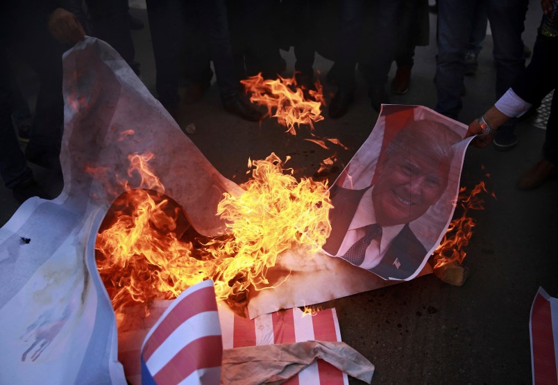 Palestinian protesters burn a poster of U.S. President Donald Trump and mocks of Israeli and American flags, during a protest against US decision to recognize Jerusalem as Israel’s capital, in Gaza City Thursday, Dec. 7, 2017. (AP Photo/ Khalil Hamra)