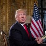 President Donald Trump turns to talk to the gathered media during a Christmas Eve video teleconference with members of the mIlitary at his Mar-a-Lago estate in Palm Beach, Fla., Sunday, Dec. 24, 2017. (AP Photo/Carolyn Kaster)