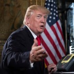 President Donald Trump turns to talk to the gathered media during a Christmas Eve video teleconference with members of the mIlitary at his Mar-a-Lago estate in Palm Beach, Fla., Sunday, Dec. 24, 2017. (AP Photo/Carolyn Kaster)