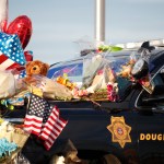 Tributes to a deputy killed in a shootout cover a patrol vehicle parked outside a Douglas County, Colo., Sheriffs Department substation Monday, Jan. 1, 2018, in Highlands Ranch, Colo. The deputy was killed and four other deputies were shot while responding to a call at a nearby apartment complex early Sunday. (AP Photo/David Zalubowski)