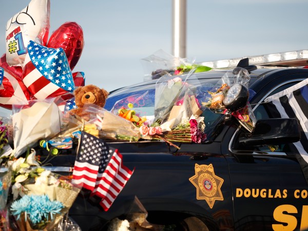 Tributes to a deputy killed in a shootout cover a patrol vehicle parked outside a Douglas County, Colo., Sheriffs Department substation Monday, Jan. 1, 2018, in Highlands Ranch, Colo. The deputy was killed and four other deputies were shot while responding to a call at a nearby apartment complex early Sunday. (AP Photo/David Zalubowski)