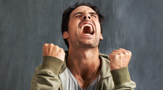 A young man yelling in frustration with his eyes closed