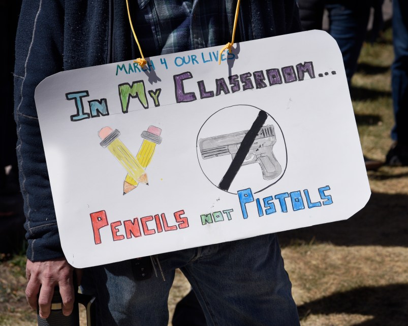 SANTA FE, NM - MARCH 24, 2018:  A school teacher wears a sign around his neck expressing his opposition to arming teachers during a 'March For Our Lives' rally in Santa Fe, New Mexico. The rally and march, part of a nationwide series of similar events in response to school shootings, brought together gun control advocates urging legislation to reduce gun violence and the sale and public ownership of assault rifles in the United States. (Photo by Robert Alexander/Getty Images)