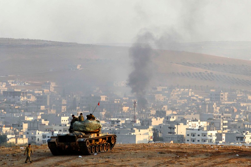 SANLIURFA, TURKEY -  OCTOBER 9: Turkish soldiers on a tank hold their positions on a hilltop in the outskirts of Suruc, Turkey, at the Turkey-Syria border, overlooking smoke rising from a strike in Kobani, Syria, during fighting between Syrian Kurds and the militants of Islamic State group, Thursday, Oct. 9, 2014. Kobani, also known as Ayn Arab, and its surrounding areas, has been under assault by extremists of the Islamic State group since mid-September and is being defended by Kurdish  fighters. (Photo by Gokhan Sahin/Getty Images)