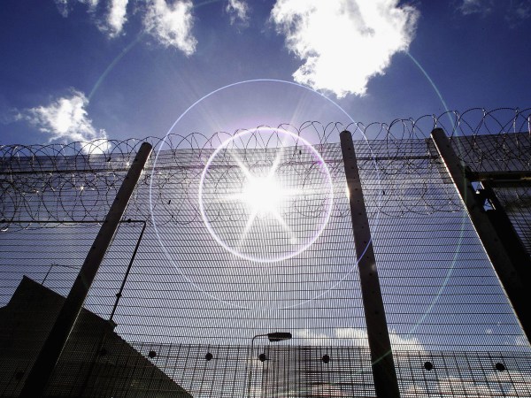 NORWICH, UNITED KINGDOM - AUGUST 25:  (EDITORS NOTE: IMAGES EMBARGOED FOR PUBLICATION UNTIL 0001GMT AUGUST 26, 2005; NATURAL LENS FLARE VISIBLE IN IMAGE) The sun shines through high security fencing surrounding Norwich Prison on August 25, 2005 in Norwich, England. A Chief Inspector of Prisons report on Norwich Prison says healthcare accommodation was among the worst seen, as prisoners suffered from unscreened toilets, little natural light, poor suicide prevention, inadequate education and training for long-term prisoners. (Photo by Peter Macdiarmid/Getty Images)