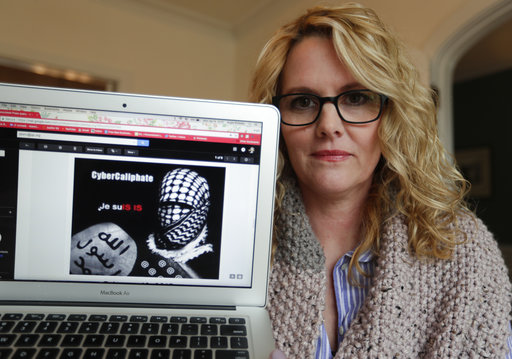 ** HOLD FOR STORY BY RAPHAEL SATTER ** Angela Rickett poses with a screen shot of a message she received from a group claiming to be Islamic State supporters in Bloomington, Ind., Monday, April 9, 2018. Russian spies masquerading as Islamic State supporters threatened outspoken U.S. Army spouses, The Associated Press found, in an operation that presaged the infamous chaos campaign of Russian social media trolls during the American election.(AP Photo/Michael Conroy)
