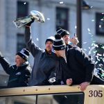 PHILADELPHIA, PA - FEBRUARY 08: (L-R) Team owner Jeffrey Lurie, with quarterbacks Nick Foles #9, Nate Sudfeld #7 and Carson Wentz #11 of the Philadelphia Eagles, acknowledge fans as Foles hoists the Vince Lombardi Trophy atop a parade bus during festivities on February 8, 2018 in Philadelphia, Pennsylvania. The city celebrated the Philadelphia Eagles' Super Bowl LII championship with a victory parade. (Photo by Corey Perrine/Getty Images)