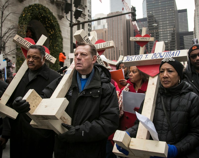 FILE -  In this Dec. 31, 2016 file photo, The Rev. Michael Pfleger, center, Rev. Jesse Jackson, left, and state Sen. Jacqueline Collins, right, led hundreds in a march down Michigan Avenue, carrying crosses for all those killed by Chicago violence in 2016 and to call for an end to violence in Chicago. Protesters planning to shut down a major Chicago interstate on Saturday, July 7, 2018, say they’re trying to increase pressure on public officials to address the gun violence that’s claimed hundreds of lives in some of the city’s poorest neighborhoods. (Ashlee Rezin/Chicago Sun-Times via AP)