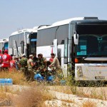 In this photo released by the Syrian official news agency SANA, ﻿Syrian government forces and Syrian Arab Red Crescent oversee the evacuation by buses of opposition fighters and their families from the southern province of Daraa, Syria, Sunday, July 15, 2018. The evacuation deal will hand over areas held by the rebels for years back to government control. Daraa, which lies on a highway linking Damascus with Jordan, was the cradle of the 2011 uprising against Syrian President Bashar Assad. (SANA via AP)