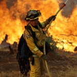 A firefighter makes a stand in front of an advancing wildfire as it approaches a residence Saturday, July 28, 2018, in Redding ,Calif. (AP Photo/Marcio Jose Sanchez)