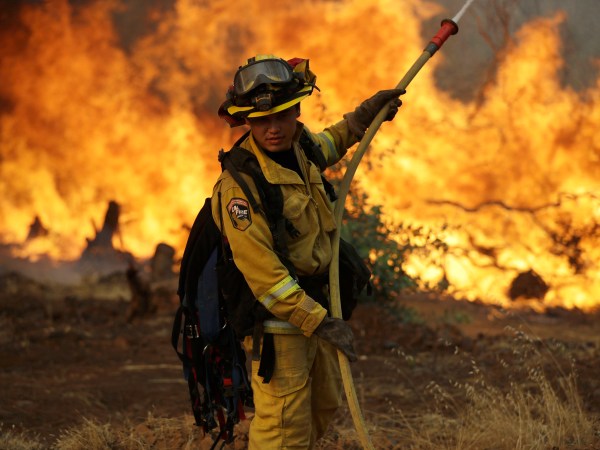 A firefighter makes a stand in front of an advancing wildfire as it approaches a residence Saturday, July 28, 2018, in Redding ,Calif. (AP Photo/Marcio Jose Sanchez)