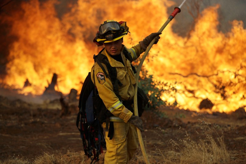 A firefighter makes a stand in front of an advancing wildfire as it approaches a residence Saturday, July 28, 2018, in Redding ,Calif. (AP Photo/Marcio Jose Sanchez)
