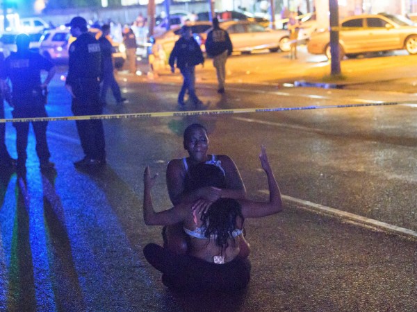 People react at the scene of the 3400 block of South Claiborne Street where two people are dead and seven more injured in a shooting in New Orleans, La. Saturday, July 28, 2018. (AP Photo/The New Orleans Advocate,Matthew Hinton)