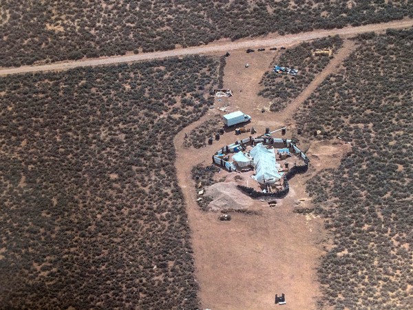 FILE - This Friday, Aug. 3, 2018, aerial file photo released by Taos County Sheriff's Office shows a rural compound during an unsuccessful search for a missing 3-year-old boy in Amalia, N.M. Authorities say they've arrested three women believed to be the mothers of 11 children found living in filth in a makeshift compound in rural northern New Mexico. Taos County, New Mexico, Sheriff Jerry Hogrefe said Monday, Aug. 6, 2018, that the women and two men who were arrested over the weekend face charges of child abuse. (Taos County Sheriff's Office via AP, File)