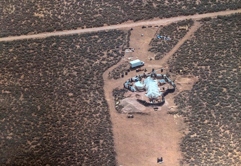 FILE - This Friday, Aug. 3, 2018, aerial file photo released by Taos County Sheriff's Office shows a rural compound during an unsuccessful search for a missing 3-year-old boy in Amalia, N.M. Authorities say they've arrested three women believed to be the mothers of 11 children found living in filth in a makeshift compound in rural northern New Mexico. Taos County, New Mexico, Sheriff Jerry Hogrefe said Monday, Aug. 6, 2018, that the women and two men who were arrested over the weekend face charges of child abuse. (Taos County Sheriff's Office via AP, File)