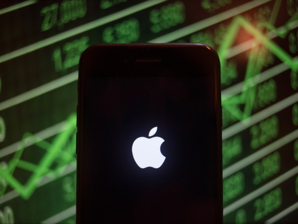BANGKOK, THAILAND - 2018/07/30: An iPhone displays the Apple logo with a background of a market value increasing on the stock exchange behind. (Photo by Guillaume Payen/SOPA Images/LightRocket via Getty Images)
