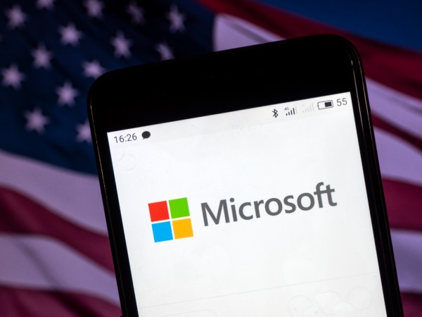 KIEV, UKRAINE - 2018/08/06: The Microsoft logo seen displayed on a smart phone with a background of an American Flag. According to the New York Stock Exchange (NYSE), the company is on the fourth place at the market value in the world - $ 825.8 billion. (Photo by Igor Golovniov/SOPA Images/LightRocket via Getty Images)