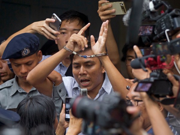 Reuters journalist Kyaw Soe Oo, center, talks to journalists during he is escorted by polices as they leave the court Monday, Sept. 3, 2018, in Yangon, Myanmar. (AP Photo/Thein Zaw)